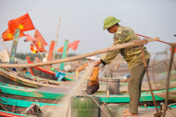 Fishermen repairing nets on a boat trip out to sea in the afternoon July 31, 2016 at the beach of Hai Ly, Vietnam.