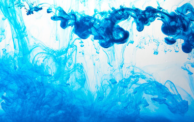 Closeup of a blue ink in water in motion isolated on white. Ink swirling underwater. Colored abstract smoke explosion effect. Abstract background with copy space..