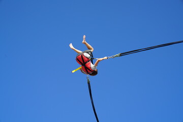 The people entertains herself by jumping on a bungee catapult. The catapult trampoline at the top...