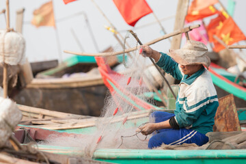 Fishermen repairing nets on a boat trip out to sea in the afternoon July 31, 2014 at the beach of Hai Ly, Vietnam.