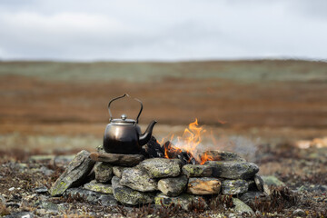 Camping kettle near camp fire. Camping place in wild. Wonderful atmospheric background of campfire....