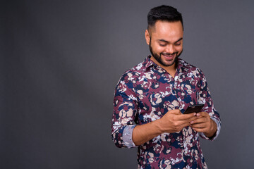 Young bearded Indian man against gray background