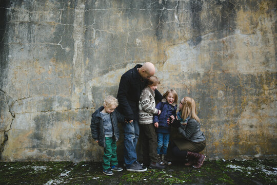 Happy young family of five having fun near concrete wall - outside in winter