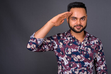 Young bearded Indian man against gray background