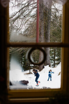 Kids' Snowball Fight Outdoors Seen Through A Decorated Window From Inside