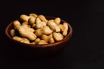 peanuts in a wooden plate on a black background