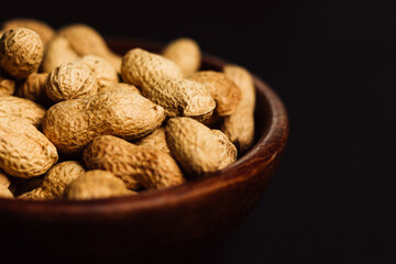 peanuts in a wooden plate on a black background