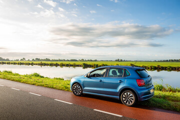 A blue parked car on the side of the road near the ringvaart canal in the North-Holland village of...