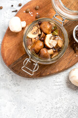 Pickled mushrooms in a glass jar close-up. Marinated mushrooms with pepper and bay leaf. Food preserving for autumn or winter time