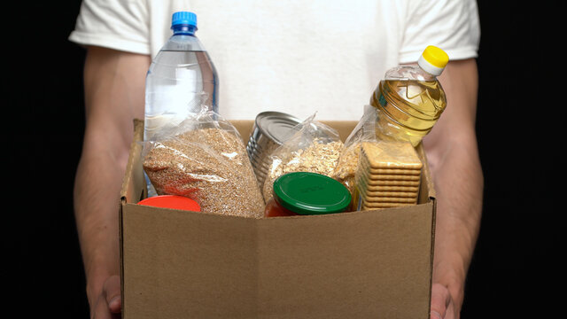 Volunteer Putting Food In A Donation Box. Charity Concept.