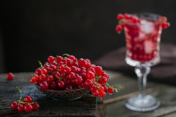 Heap of fresh red currant with water drops in a metal bowl on old dark wooden background. Healthy eating and diet food concept.