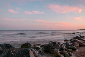 rocky sea shore before sunrise, dark stone silhouettes and colorful sky