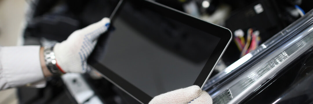 Mechanic holding tablet to diagnose auto condition. Read auto trouble codes. Checking vehicle readiness status. EGR exhaust system test. Read vehicle information on an electronic device