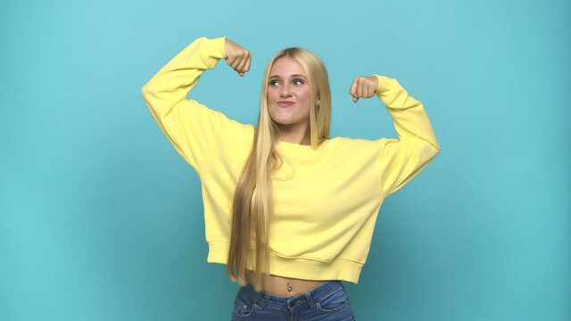 Young caucasian blonde woman showing strength gesture with arms, symbol of feminine power