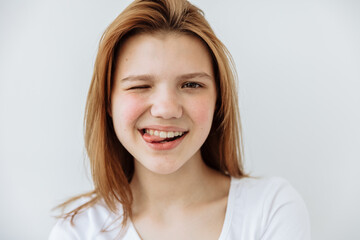 Naklejka premium Teen girl showing tongue and wink against white background