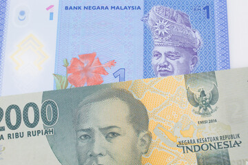 A macro image of a grey two thousand Indonesian rupiah bank note paired up with a blue, plastic one ringgit bank note from Malaysia.  Shot close up in macro.