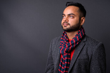 Young bearded Indian businessman against gray background