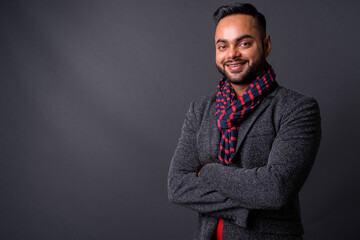 Young bearded Indian businessman against gray background