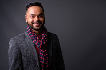 Young bearded Indian businessman against gray background