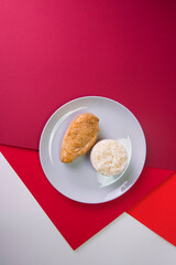 Top view of Tasty roasted chicken fillet on gray plate with boiled white rice served in culinary ring. Breakfast on colorful red background. Main and side dish in one plate.
