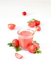 Fresh tomato juice in a glass with bamboo straws on a white background