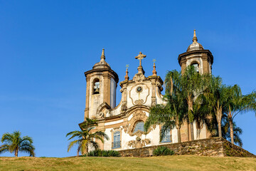 Fototapeta na wymiar Ancient and historic church in 18th century colonial architecture on top of the hill in the city of Ouro Preto in Minas Gerais, Brazil with towers and palms