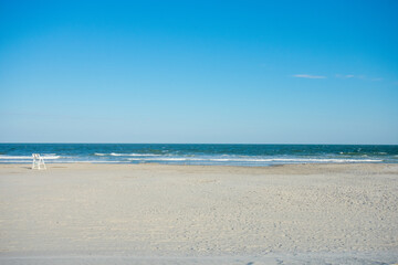 Fototapeta na wymiar An Empty Beach With a Lifeguard Chair on a Clear Blue Sky