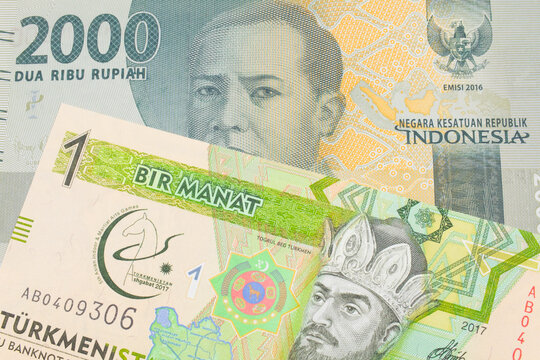 A macro image of a grey two thousand Indonesian rupiah bank note paired up with a green and yellow one manat note from Turkmenistan.  Shot close up in macro.