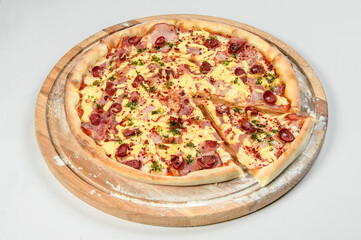 Whole uncut pizza on round wooden cutting board served with flour isolated on background. Restaurant fast food menu dish isolation. Slice of meat pizza with melted cheese.

