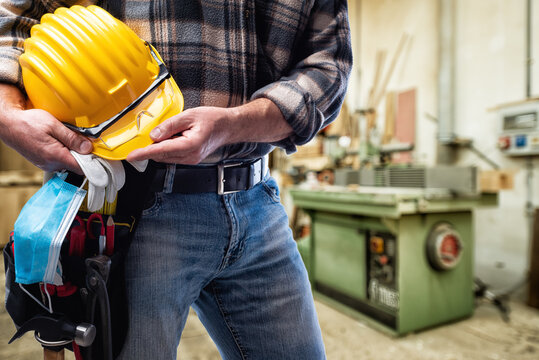 Carpenter with work tools and surgical mask on white background. Carpentry. Covid-19 prevention.