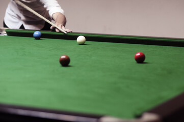 A man's hand playing snooker in a bar Snooker ball on the table. Snooker room background. for wallpaper, head website and work design.