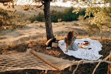 young and happy woman enjoying amazing picnic scenery with beautiful sunset.