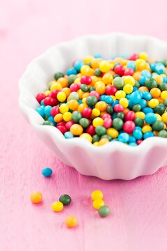 colorful sugar pearls in a bowl on pink background
