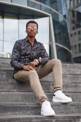 Young attractive black man in a business suit against the background of the city.