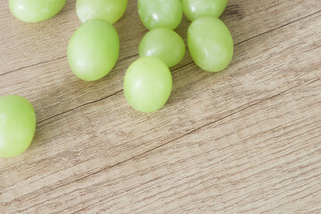 Green grapes  scattered on old wooden boards. A bunch of grapes on a wooden table. Close-up