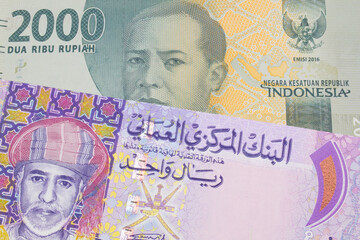 A macro image of a grey two thousand Indonesian rupiah bank note paired up with a colorful one rial note note from Oman.  Shot close up in macro.