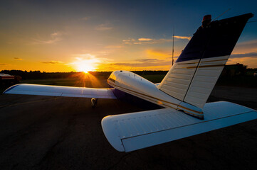 Fototapeta na wymiar Quadruple aircraft parked at a private airfield. Rear view of a plane with a propeller on a sunset background.