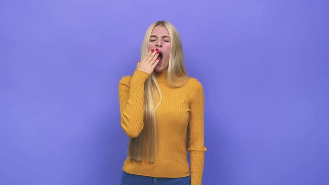 Young caucasian blonde woman yawning showing a tired gesture covering mouth with hand