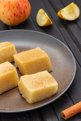 Homemade apple jelly squares with cinnamon on black background. Delicious vegan food. Vertical