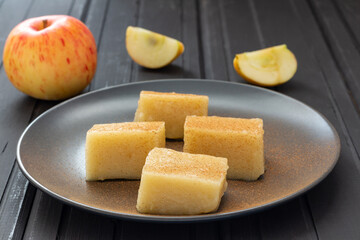 Homemade apple jelly squares with cinnamon on black plate. Delicious vegan food