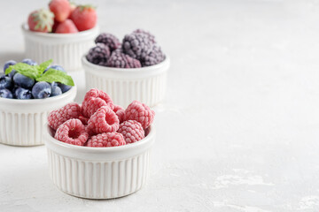Frozen berries in small bowls on a concrete background from copies of space.