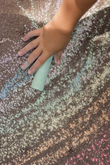 
a child draws with chalk on the asphalt