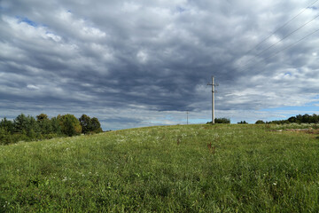 Summer landscape with green meadow and power line