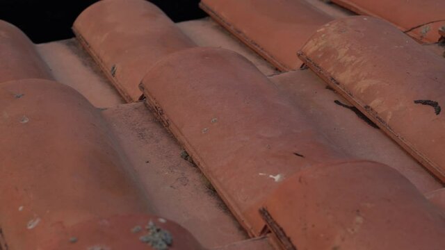 Closeup view 4k video of surface of old weathered red clay tiles construction on roof of rustic cottage.