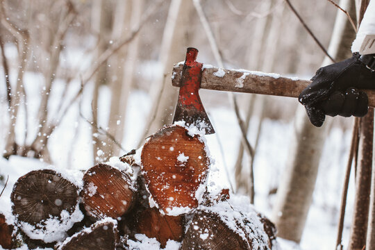 Axe stack in stacked tree trunks in a snowy forest.