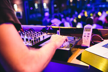 DJ playing in a disco club full of people during a party. Detail of the arm and dj set