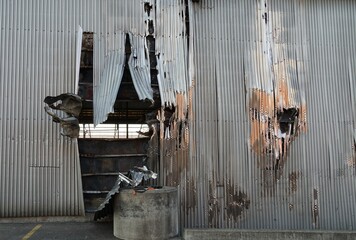Damaged aluminium corrugated plate after fire as part of the the walls of the abandoned, industrial...