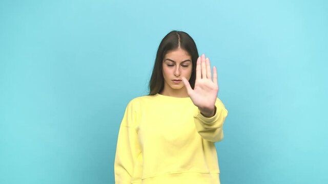 Young caucasian woman standing with outstretched hand showing stop sign, preventing you