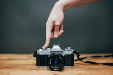 Hand pushing the button of a camera, on grey background
