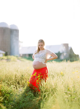 Pregnant woman walking through a field of yellow wildflowers